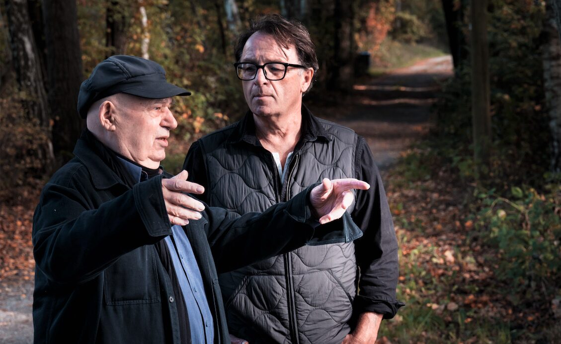 Gert Neumann und Aram Radomski auf einem Waldweg im Herbst, der Vater erklärt mit ausgebreiteten Händen